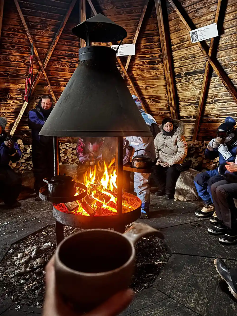 Group gathered around large central fireplace indoors
