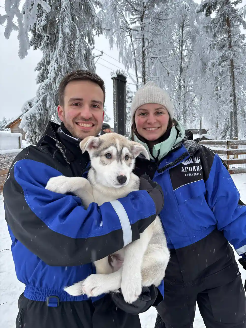 Man and woman holding husky dog in winter clothing