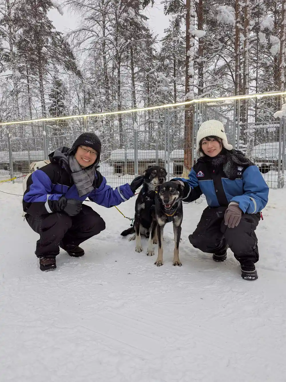 Two people crouching with black and white husky