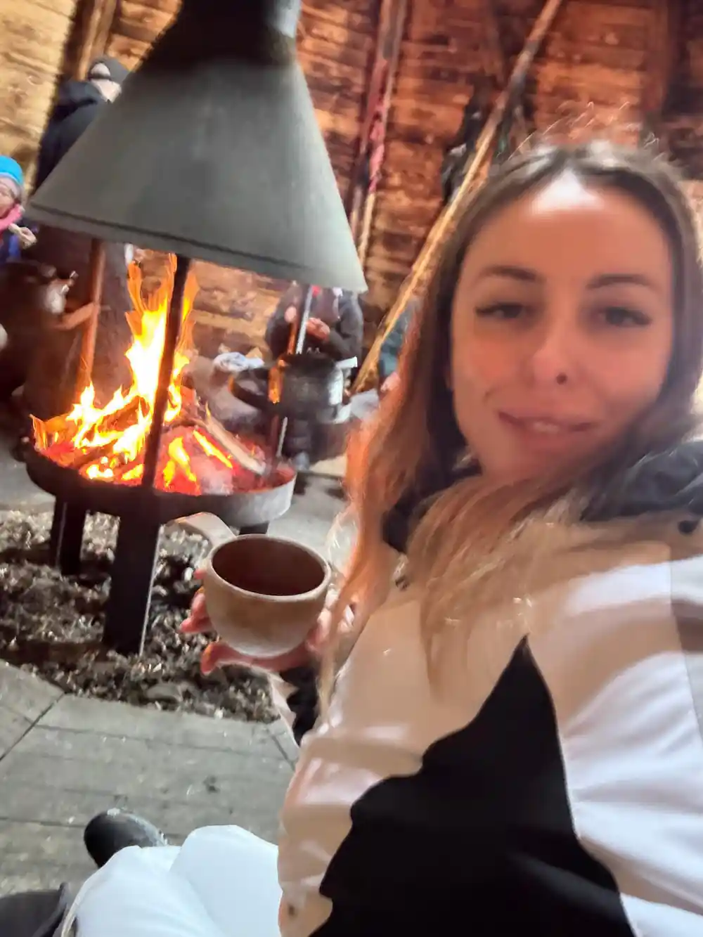 Woman by campfire with hot drink in winter