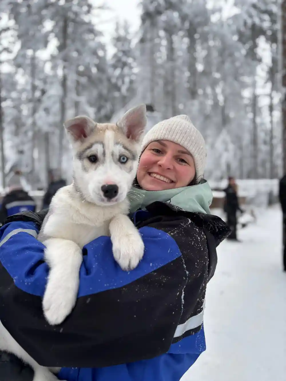 Woman holding husky puppy outdoors in winter forest