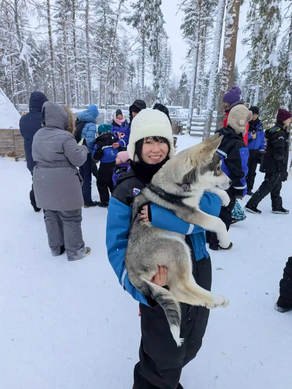 Woman holding husky puppy surrounded by people
